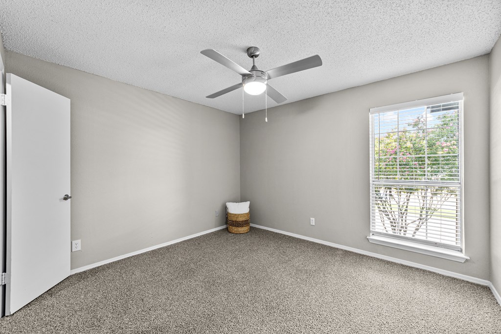 A room with a ceiling fan and a window with blinds.