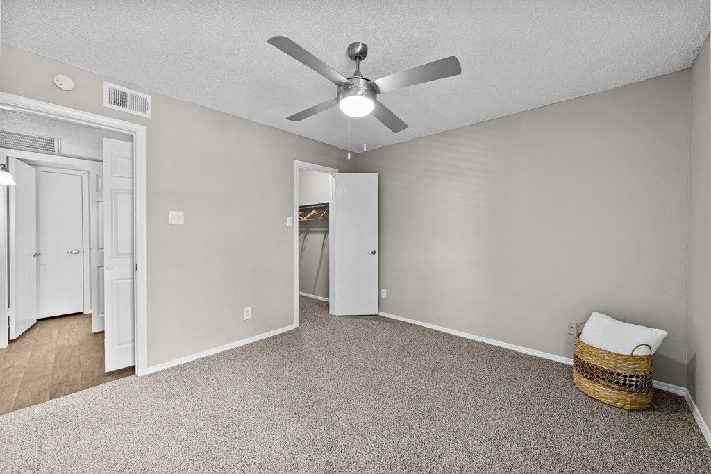 A room with a ceiling fan and a carpeted floor.
