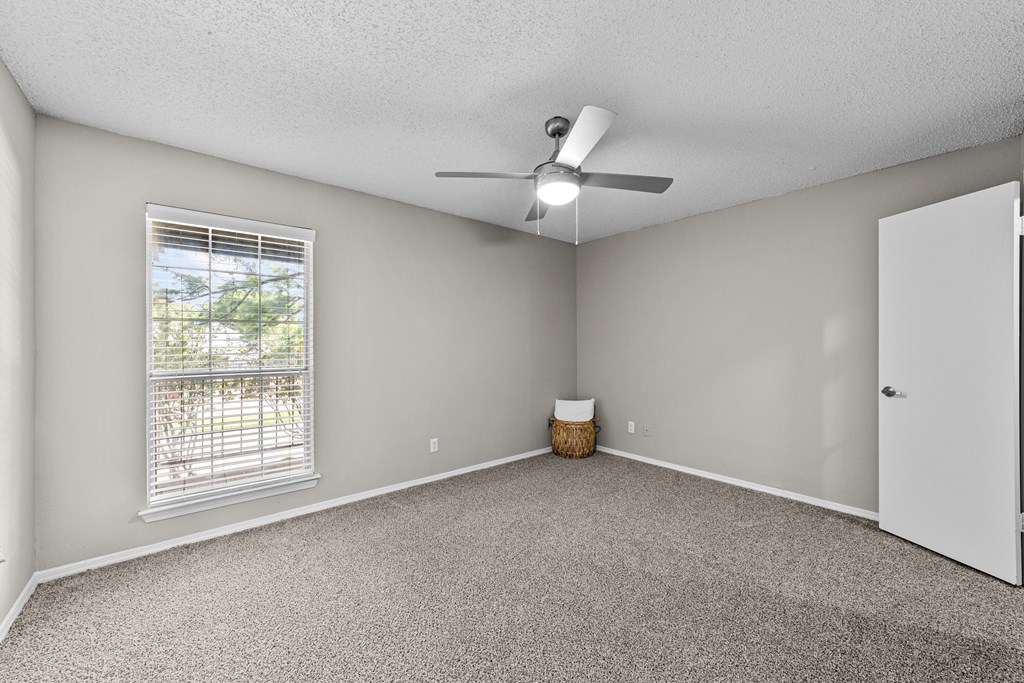 A room with a ceiling fan and a window with blinds.