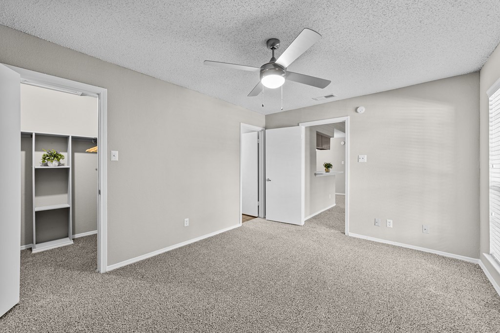 A room with a ceiling fan and carpeted floor.