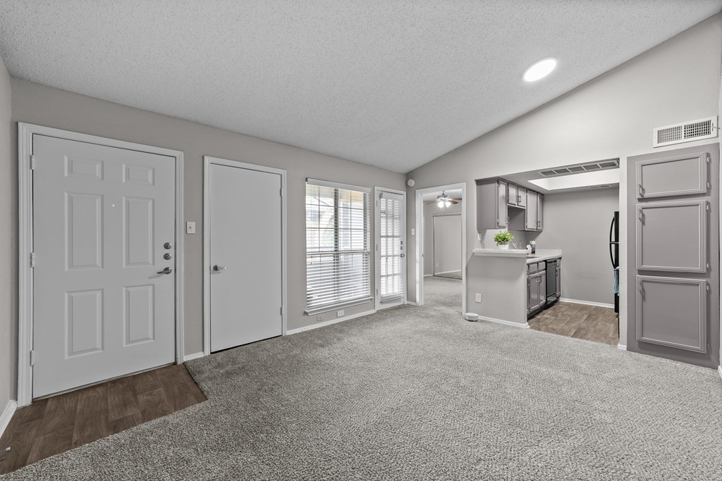 A spacious kitchen and living room with white appliances and a grey refrigerator.