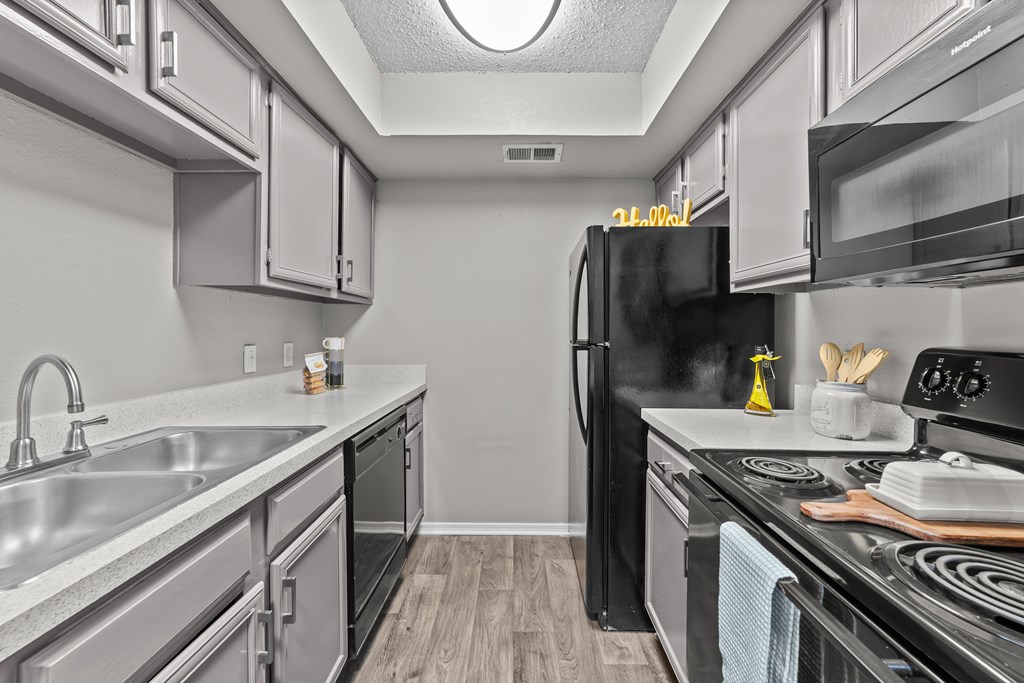 A kitchen with a black refrigerator and stove top oven.