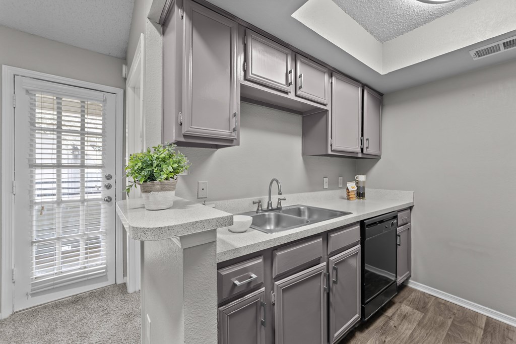 A kitchen with a sink, stove, and cabinets.