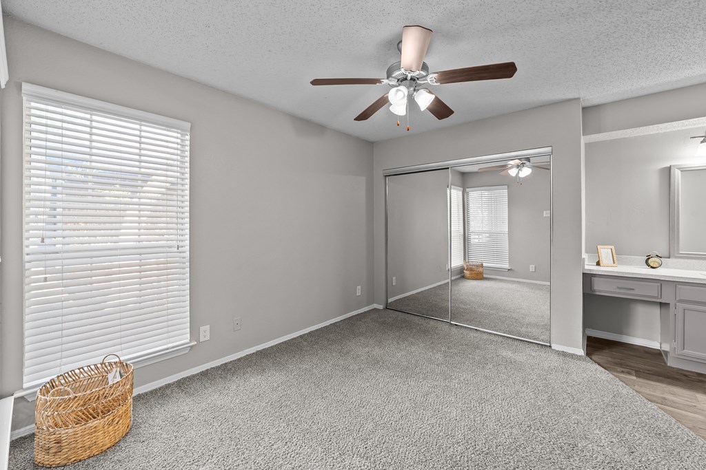 A room with a ceiling fan and a mirror on the wall.