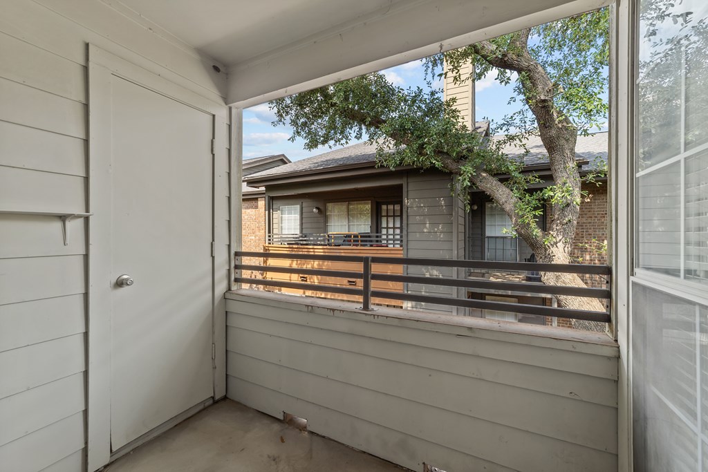 A view from a balcony looking at a house with a tree in the foreground.