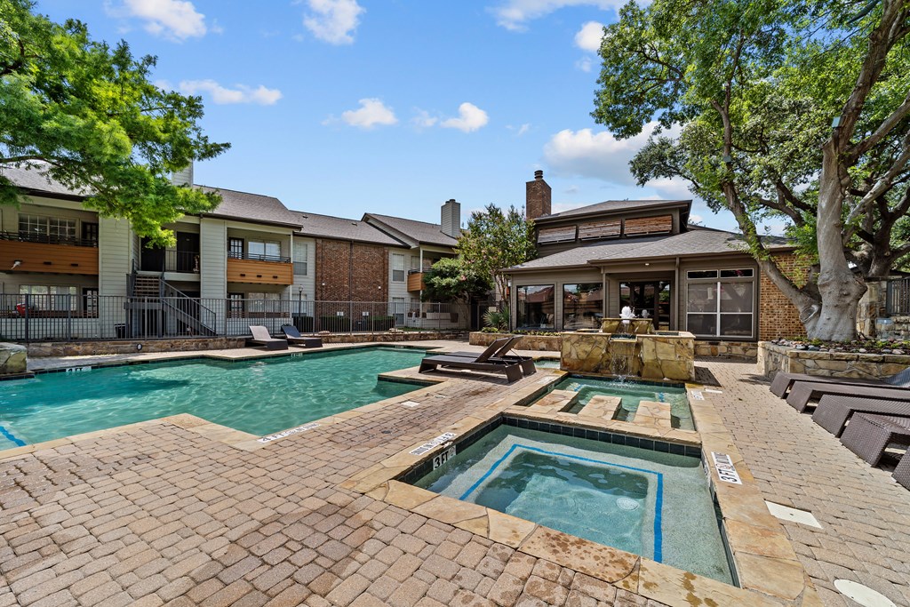 A large outdoor swimming pool with a hot tub in the middle.