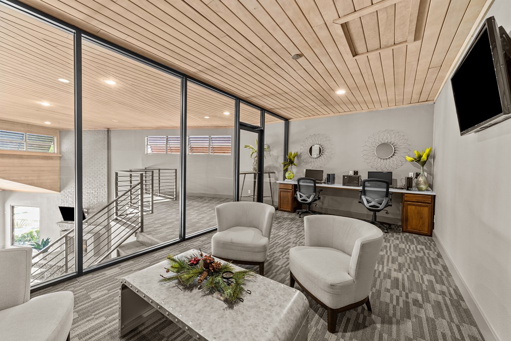 A modern living room with a wooden ceiling and a glass wall leading to a balcony.