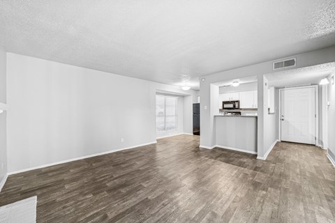 A spacious room with wooden flooring and white walls.
