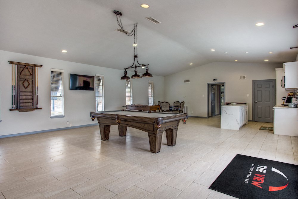 a large living room with a pool table and a kitchen