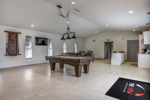 a large living room with a pool table and a kitchen