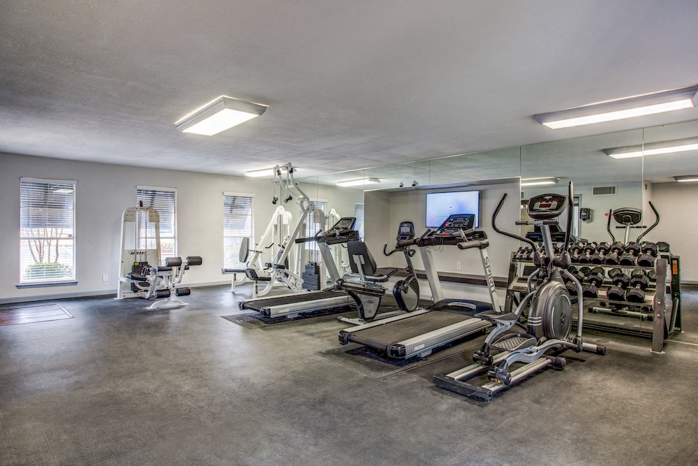 a spacious fitness room with cardio equipment and a flat screen tv