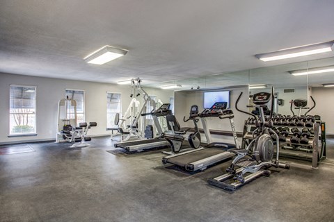 a spacious fitness room with cardio equipment and a flat screen tv