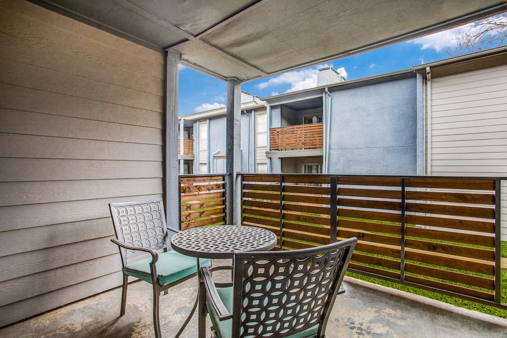 a patio with chairs and a table with a basket on top of it
