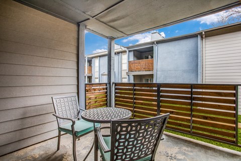 a patio with chairs and a table with a basket on top of it