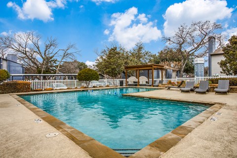 a swimming pool with a gazebo and lounge chairs next to a house