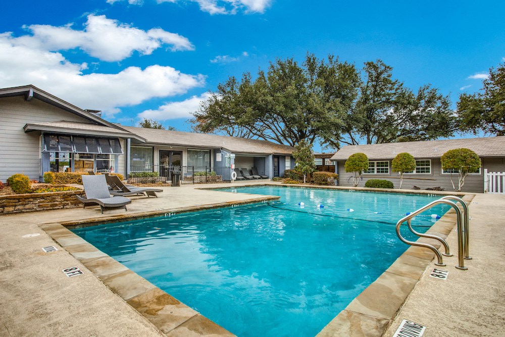 a swimming pool with lounge chairs and a house in the background