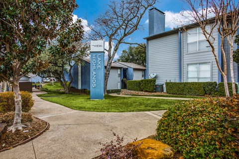 a sidewalk with a blue welcome sign in front of a house