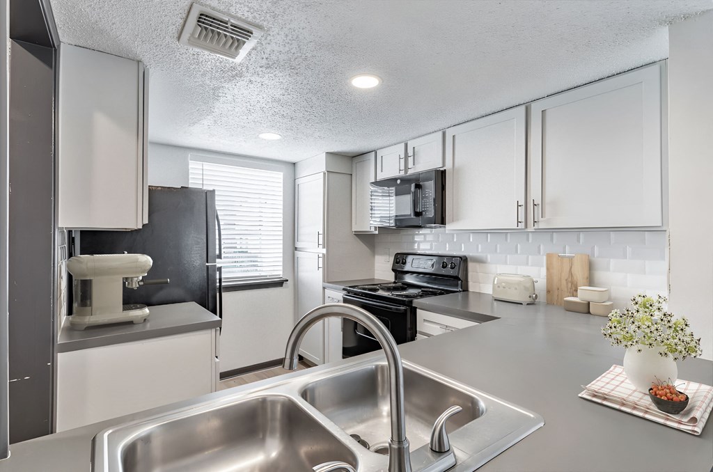 a kitchen with white cabinets and stainless steel appliances at Tradewinds, Texas
