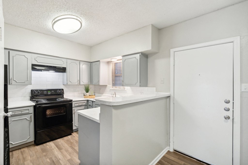 The Jackson apartment kitchen with light cabinets and black appliances