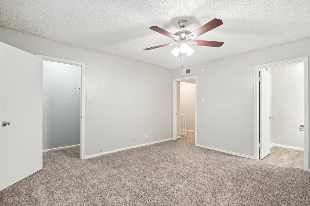 a bedroom with a ceiling fan and white walls
