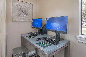 a computer desk with two monitors and a keyboard and mouse on it at Polo Clubs Apartments, Austin, TX