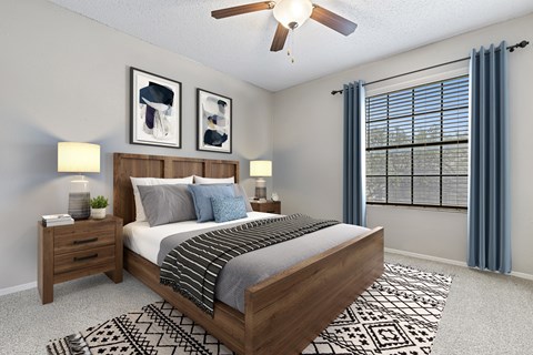 A bedroom with a large bed, a ceiling fan, and two nightstands with lamps.