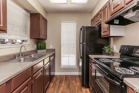 A kitchen with brown cabinets and black appliances.