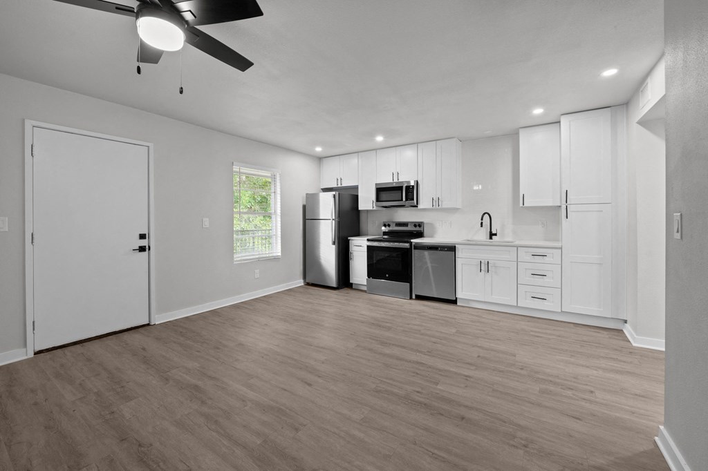 the living room and kitchen of a home with white walls and white cabinets at Sunset Heights, San Antonio, TX, 78209