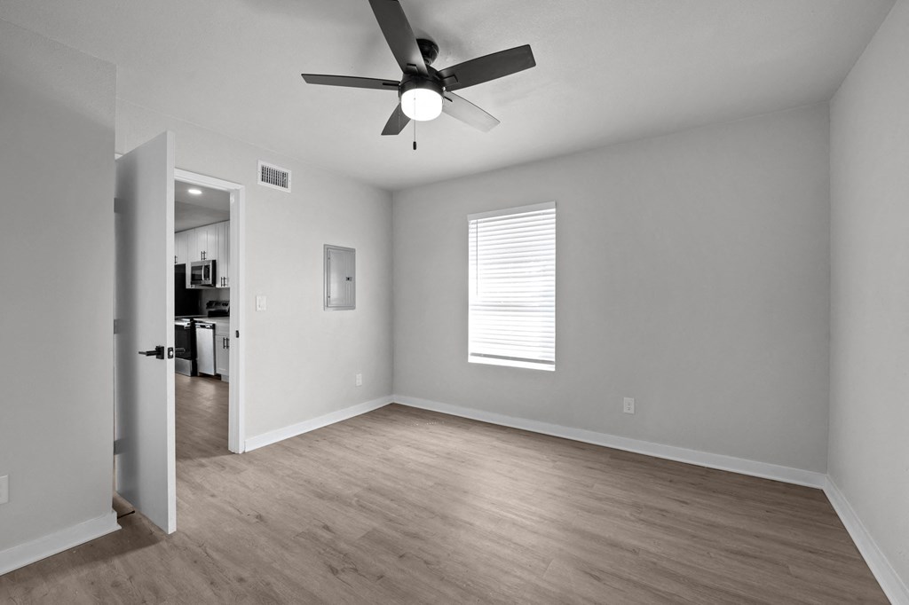 an empty living room with a ceiling fan and a door to a kitchen at Sunset Heights, San Antonio, TX