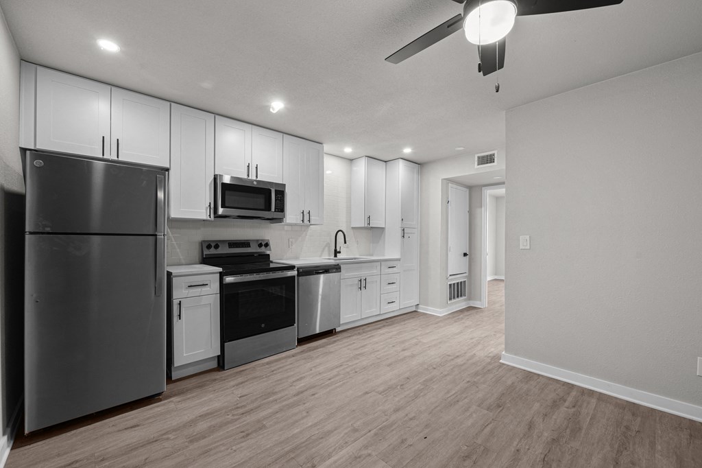 an empty kitchen with white cabinets and stainless steel appliances at Sunset Heights, Texas