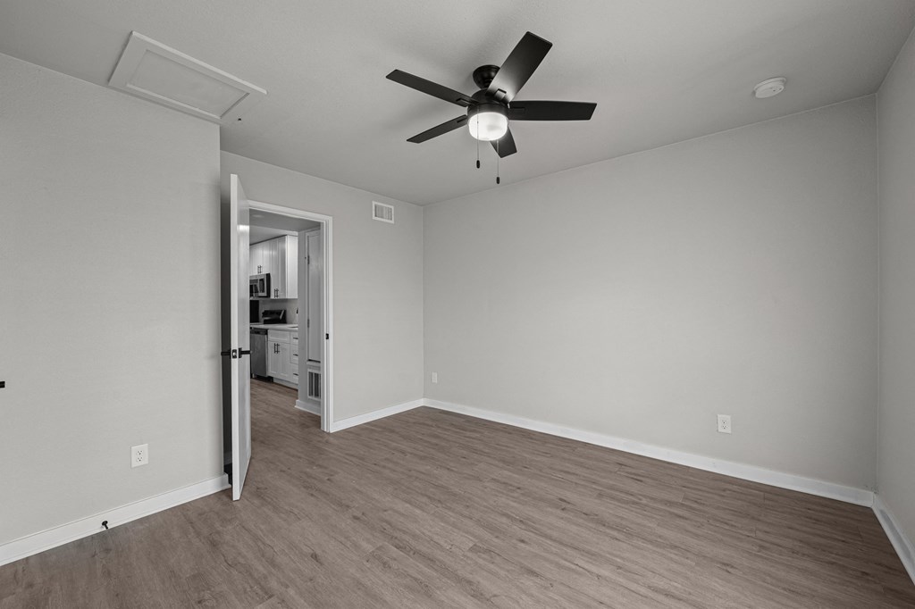 an empty living room with a ceiling fan and a door to a kitchen at Sunset Heights, San Antonio, TX