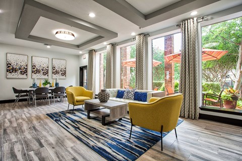 A living room with a yellow chair and a blue rug.
