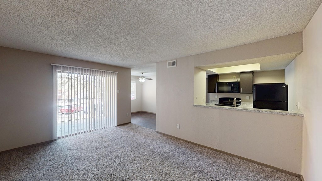 A spacious living room with a sliding glass door leading to a balcony.