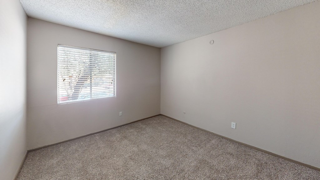 A room with a window covered by white blinds.