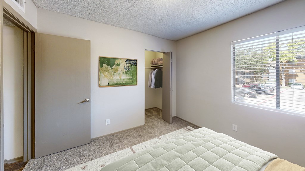 A bedroom with a bed, a painting, and a window.