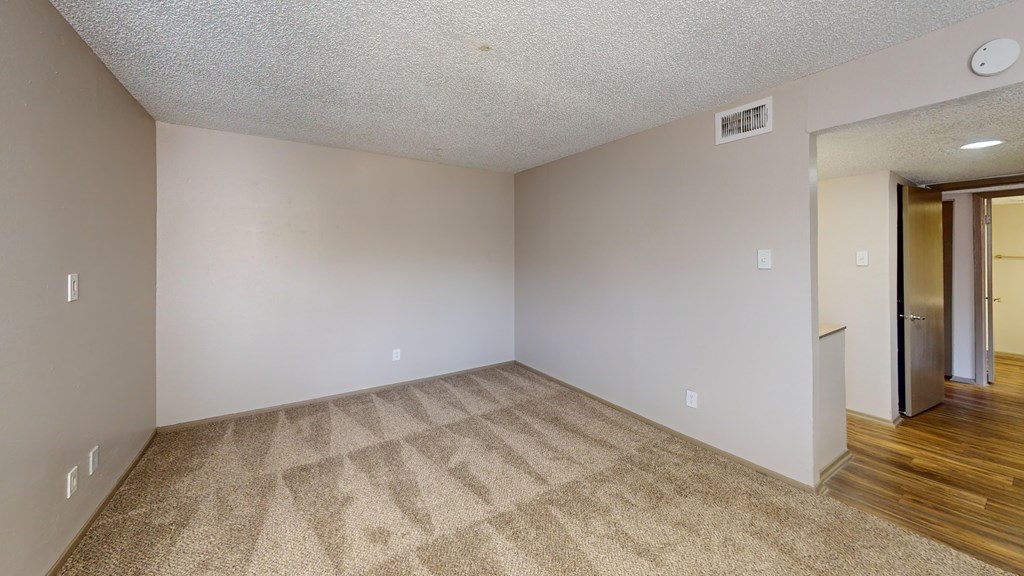 A room with a carpeted floor and a door on the right.