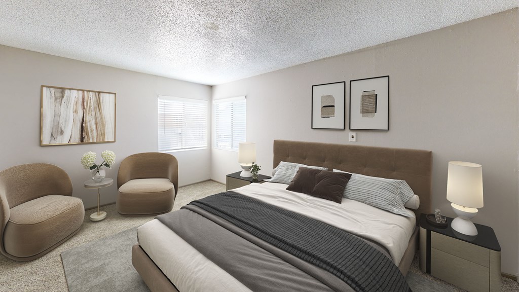 A bedroom with a large bed, two chairs, and a nightstand.