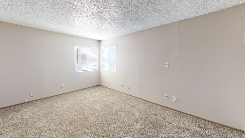 A room with a carpeted floor and a window with blinds.