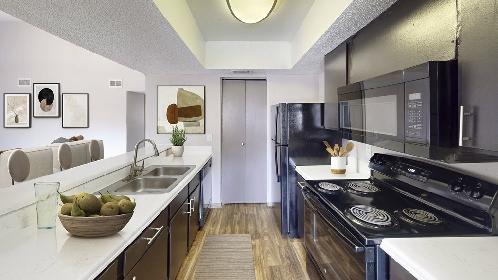 A modern kitchen with black appliances and a bowl of fruit on the counter.
