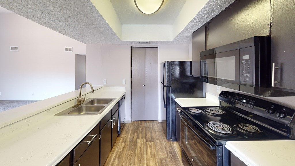 A kitchen with black appliances and white countertops.