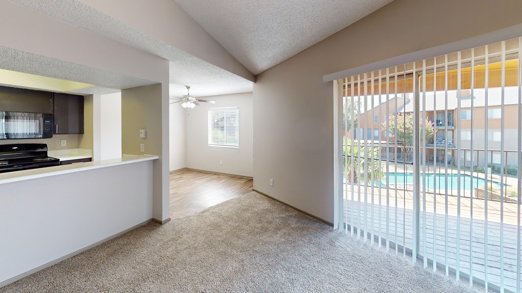A room with a carpeted floor and a sliding glass door leading to a pool area.