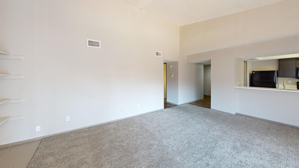 A large, empty room with a carpeted floor and white walls.