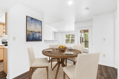 A dining room with a table set for two and a painting on the wall.