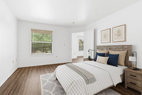 A bedroom with a large bed and a window with blinds.