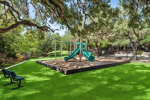 A playground with a green slide and a wooden platform.