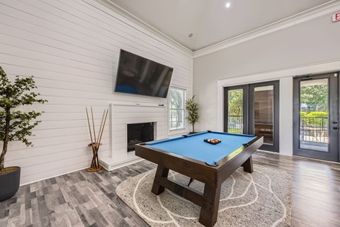 A pool table with a blue cloth and white balls is in the center of the room.