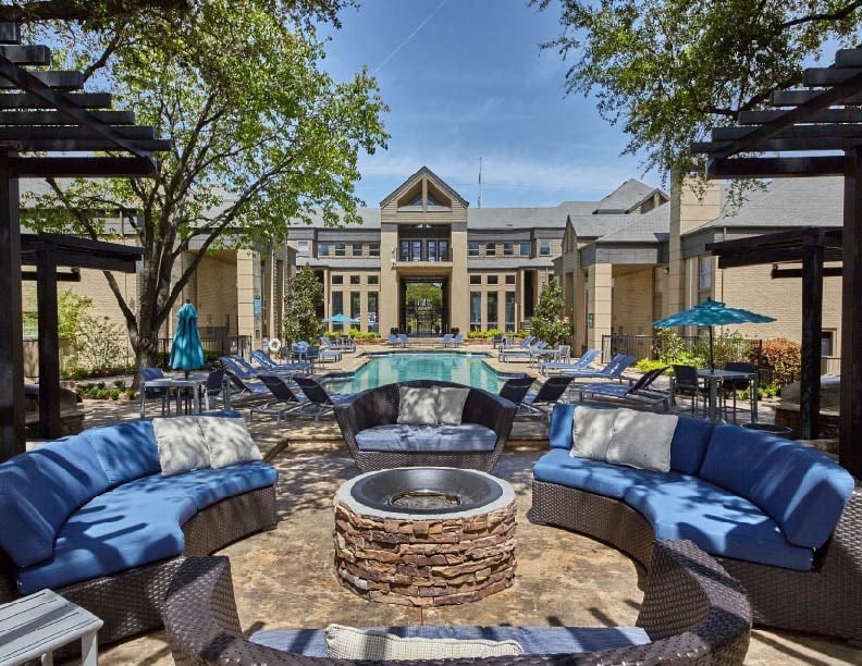 a patio with couches and a fire pit in front of a building
