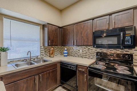 A kitchen with a black stove top oven and a black microwave above it.