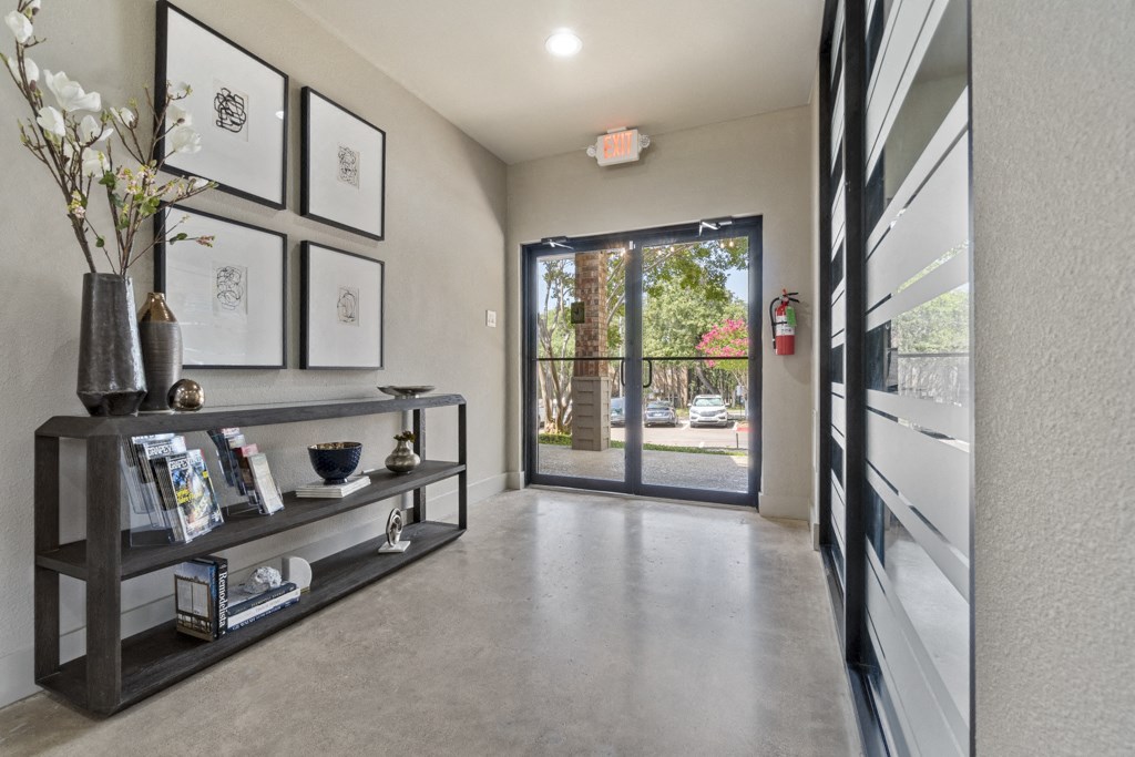the foyer of a house with a glass door and a wall shelf with pictures