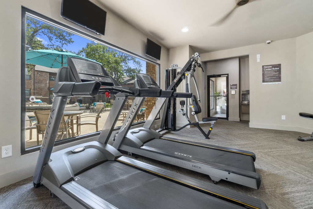 the gym is equipped with a treadmill and a large window